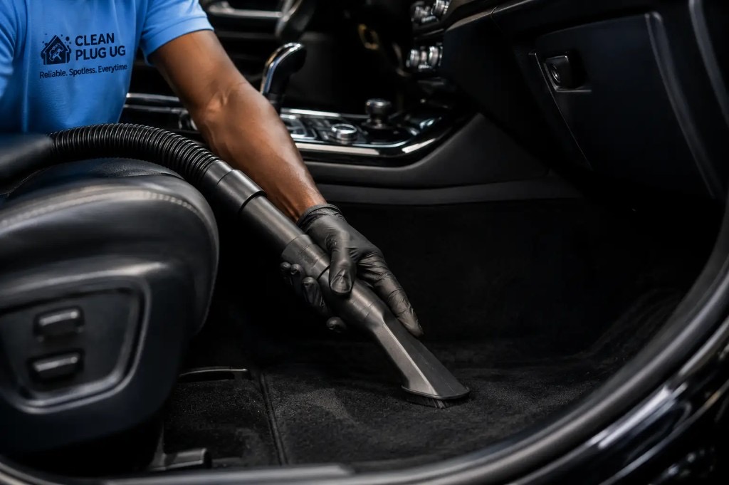 Clean Plug UG car detailing specialist vacuuming a vehicle interior carpet